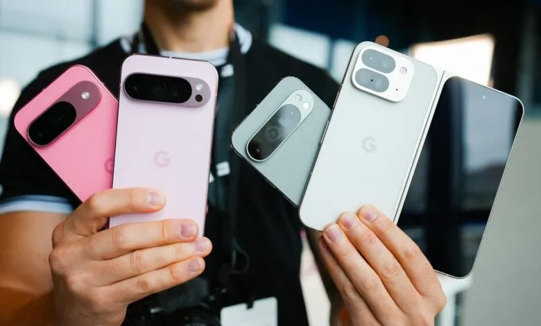 Person holding four Google Pixel phones in pink, lilac, gray, and white. The phones showcase different color options.