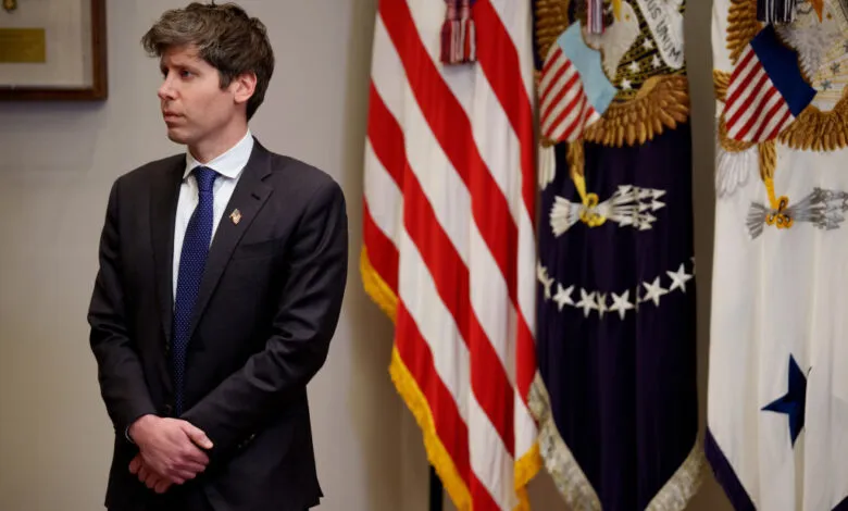 Sam Altman, OpenAI CEO, stands in a formal setting with American flags in the background.