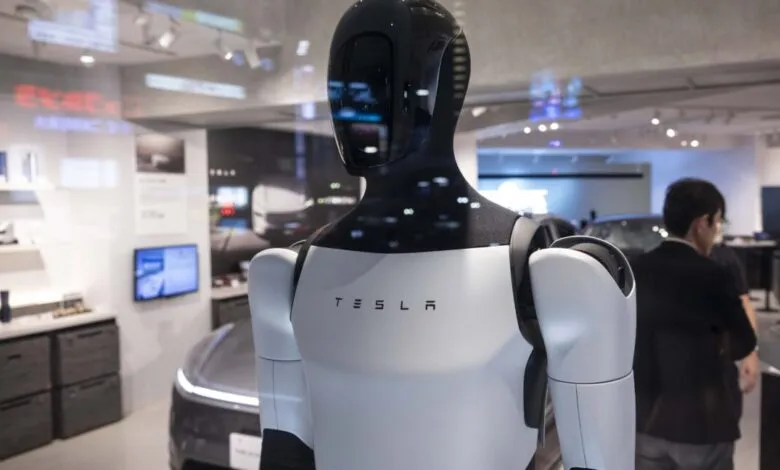 Tesla Optimus humanoid robot displayed in a Tokyo showroom. The robot is white and black, with the Tesla logo visible.