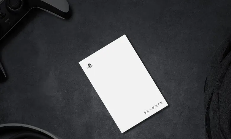 White Seagate external hard drive with PlayStation logo next to a game controller.