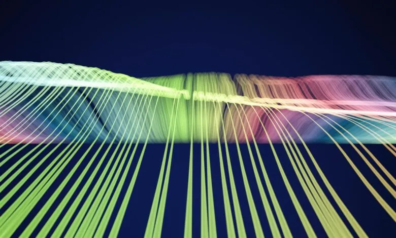 Abstract flowing lines of light in green, yellow, pink, and blue against a dark blue background.