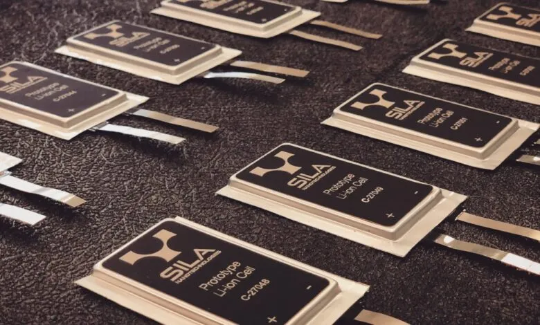 Several Sila Nanotechnologies prototype lithium-ion battery cells arranged on a dark surface.