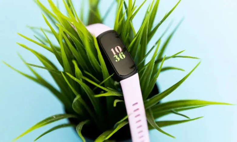 Fitbit Inspire 3 fitness tracker with a light purple band nestled in green grass.