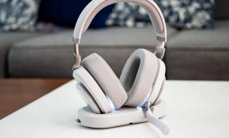 Close-up of white wireless gaming headphones on a charging stand with blue LED lights.