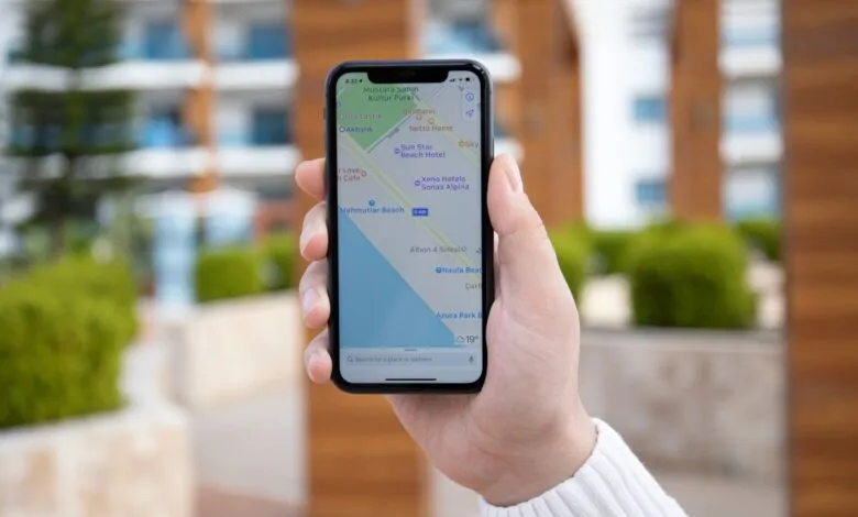Close-up of a hand holding an iPhone displaying a map application with navigation.