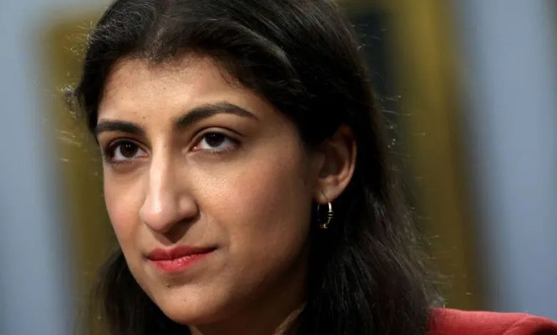 Close-up portrait of a woman with dark hair and brown eyes, wearing a red blazer.