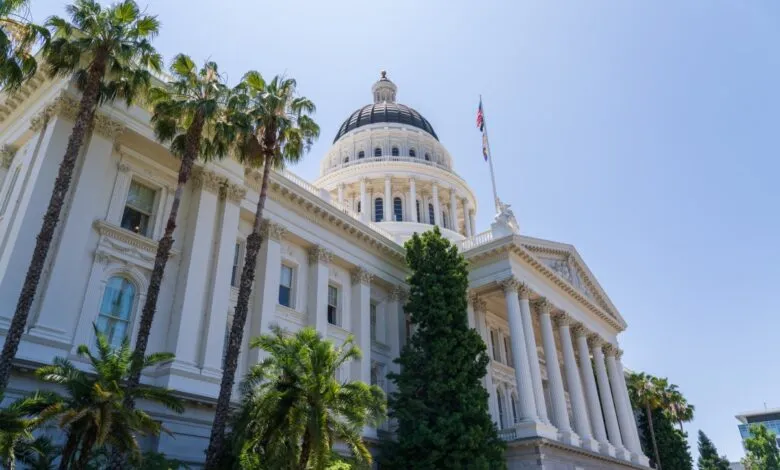 California State Capitol Building with palm trees and a clear blue sky.
