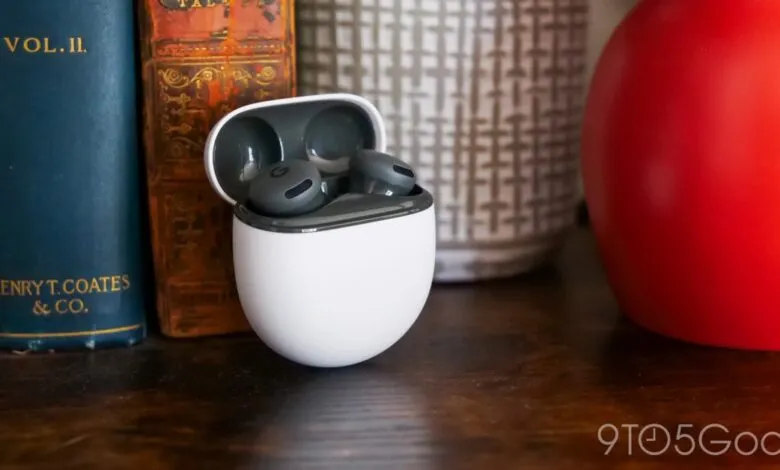 Google Pixel Buds Pro earbuds in their charging case on a wooden surface.