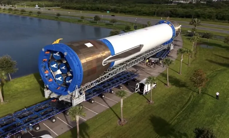 A large rocket engine section is transported on a specialized trailer.