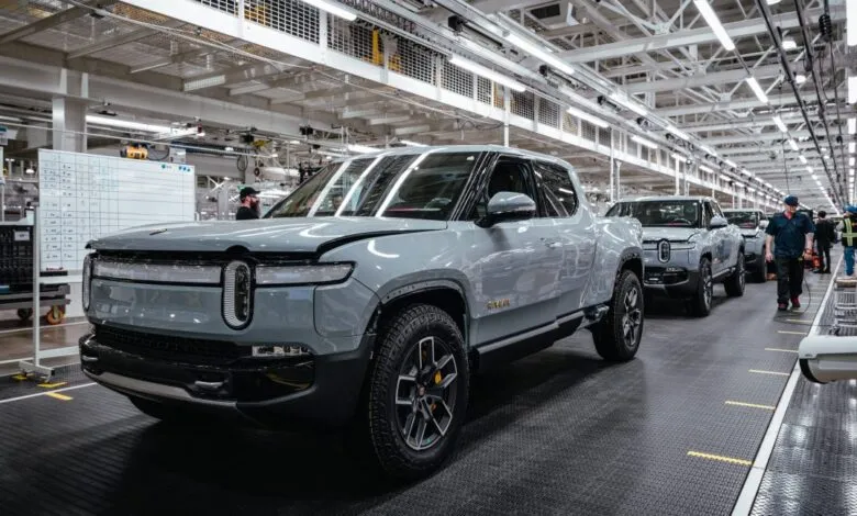 Rivian electric pickup trucks on an assembly line in a factory.