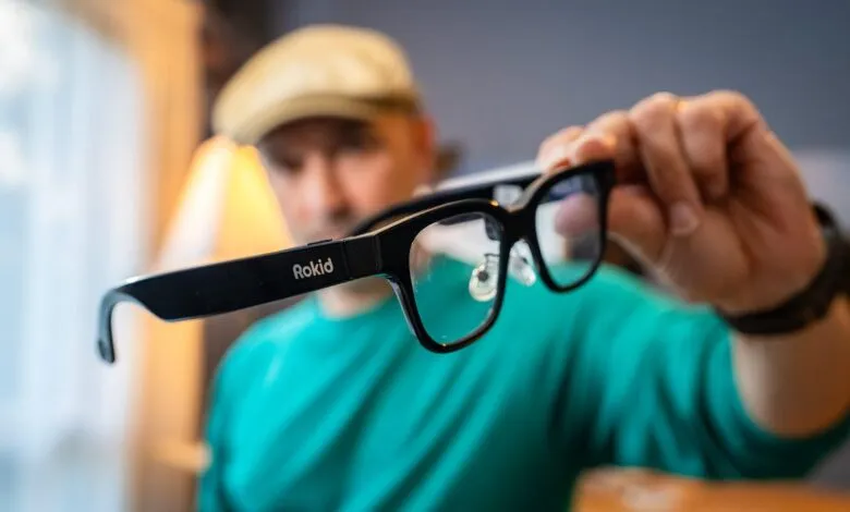 Man holding Rokid augmented reality glasses with the logo visible.