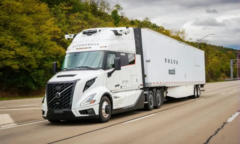 A white Volvo autonomous truck with the Waabi logo driving on a highway.