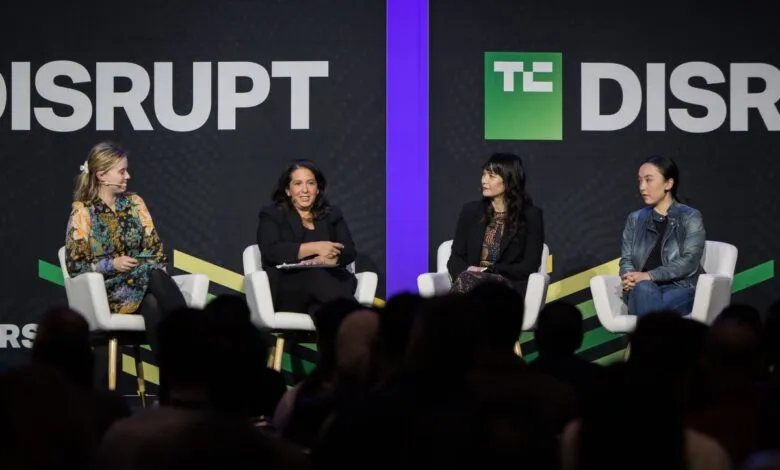 Four women sit on white chairs on a stage with 'DISRUPT' and 'TC' logos.