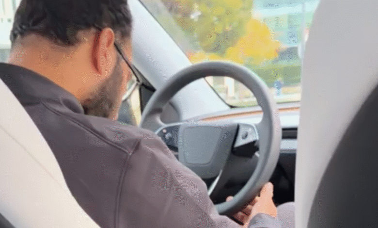 Man wearing glasses driving a car, holding the steering wheel.