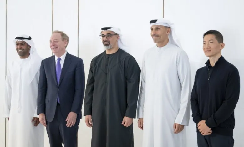 Five men in traditional Emirati attire and business suits pose for a photo.