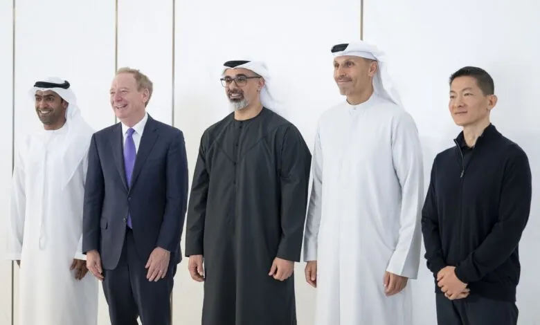 Five men in traditional and business attire stand together, smiling.