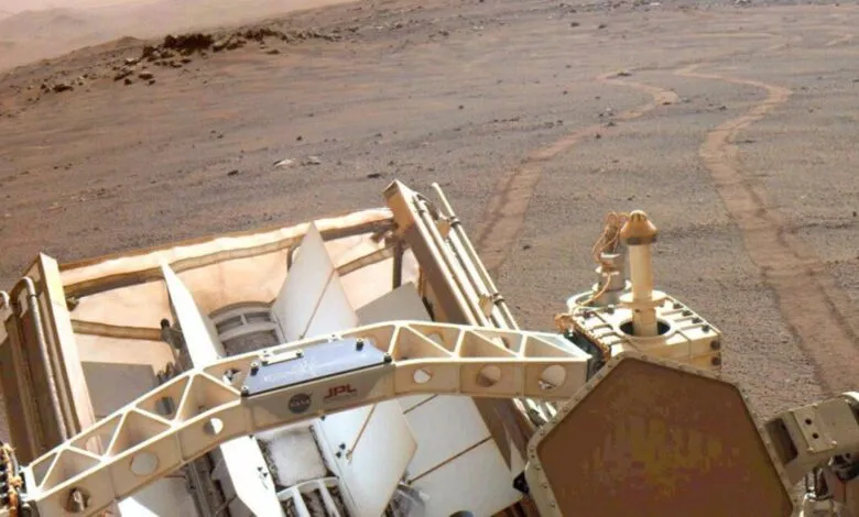 Mars rover view of red planet surface with rover tracks visible.