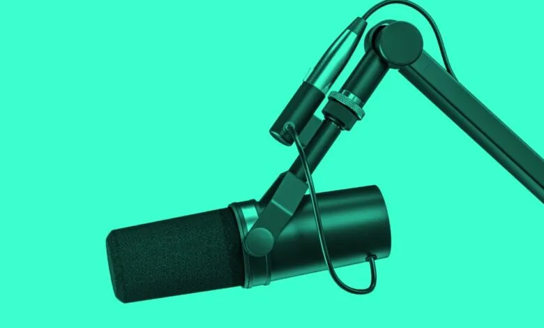 Studio microphone on boom arm against a vibrant teal background.