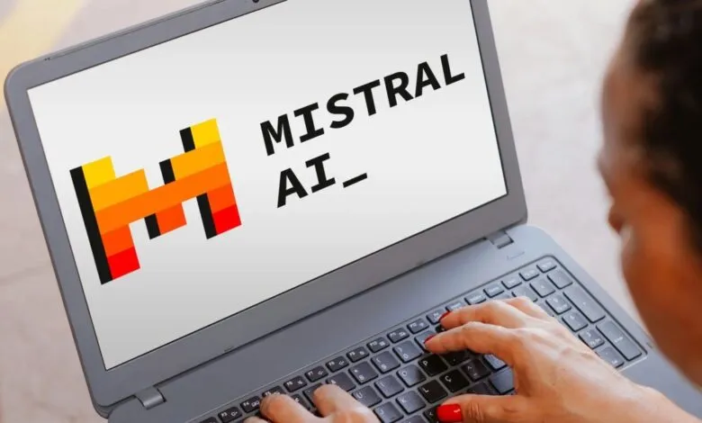 Laptop displaying Mistral AI logo with hands typing on the keyboard.