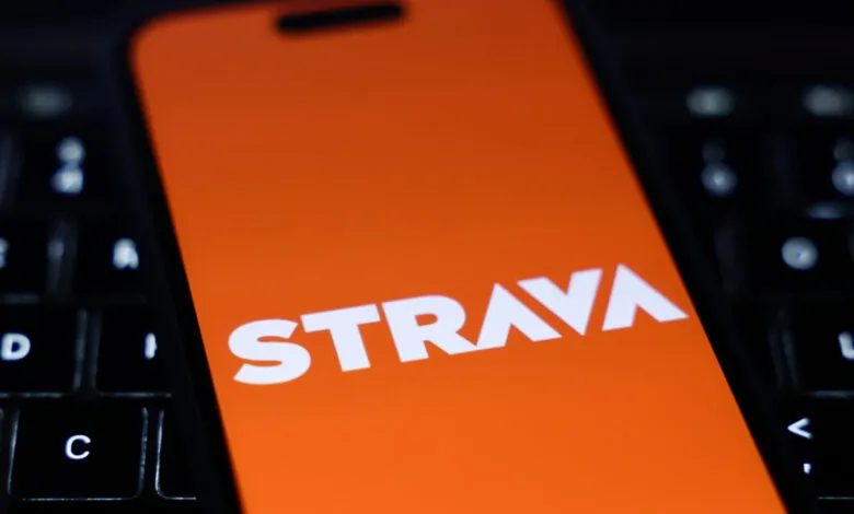Strava app displayed on phone screen atop a laptop keyboard.