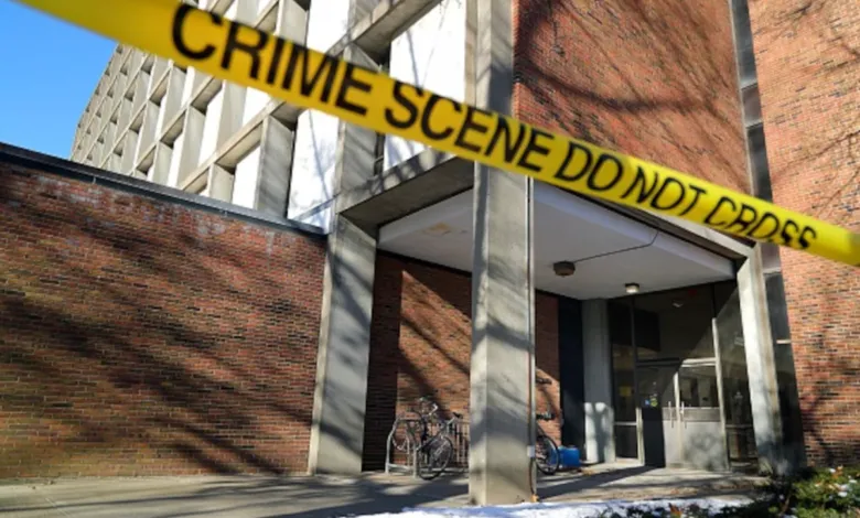 Building entrance blocked by yellow 'Crime Scene Do Not Cross' tape.