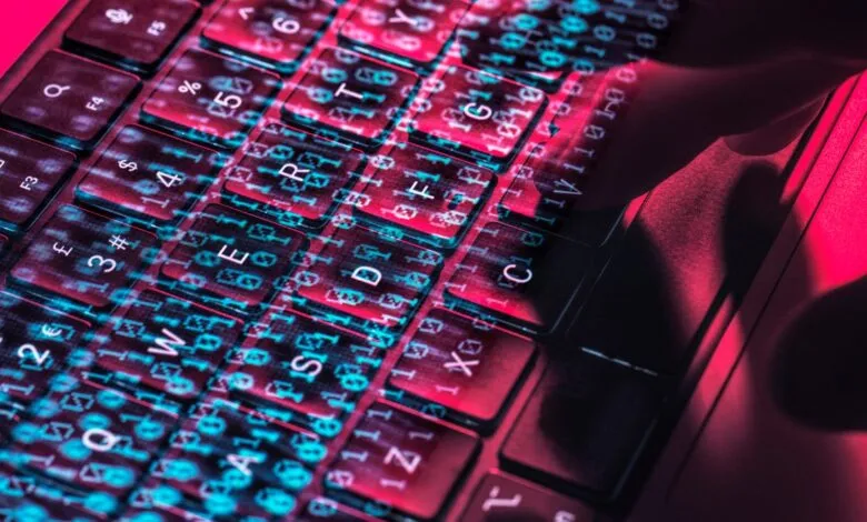 Close-up of keyboard with binary code overlay, red and blue lighting.