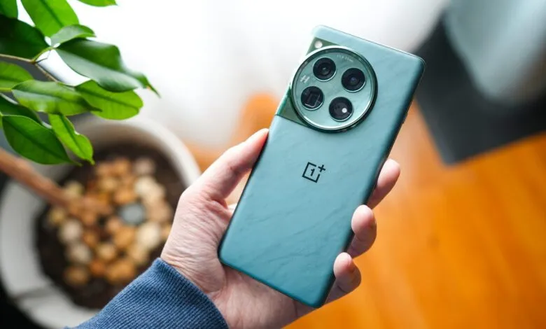 Hand holding a teal OnePlus 11 smartphone, showing the camera array.