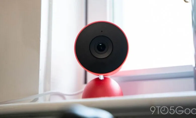 Red Nest Cam with black faceplate sits on a windowsill.