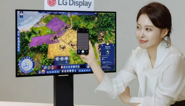 Woman presents LG Display monitor showing a mobile game.