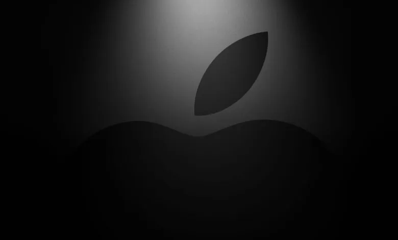 Apple logo in grayscale with a spotlight effect.