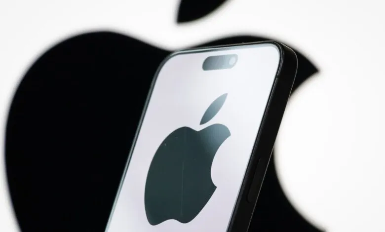 Close-up of an iPhone displaying the Apple logo against a blurred Apple logo background.