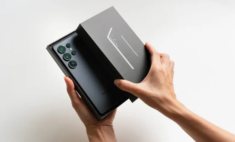 Hands opening a Samsung Galaxy S23 Ultra box, revealing the phone.