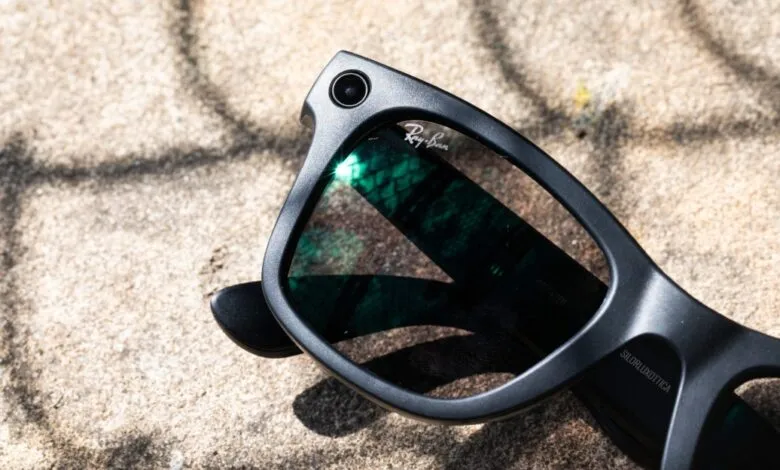 Close-up of black Ray-Ban Meta smart glasses with camera on textured surface.