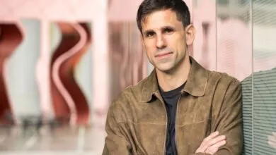 Portrait of a man in a brown jacket with arms crossed.