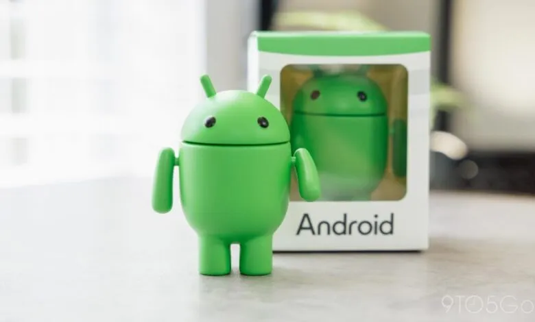 Green Android robot figure standing next to its box on a table.