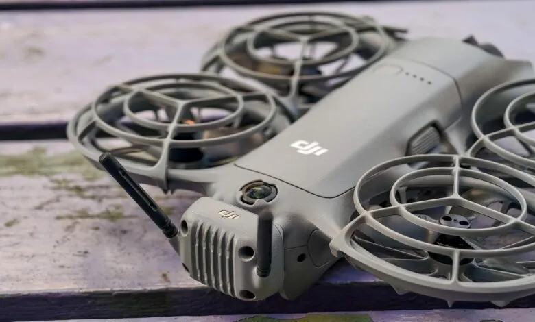 Close-up of a gray DJI drone with propeller guards on a weathered wooden surface.