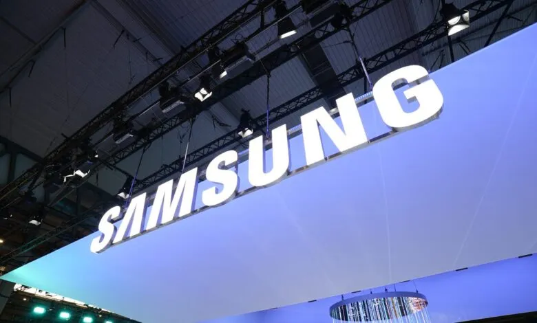 Illuminated Samsung logo suspended from a convention center ceiling.
