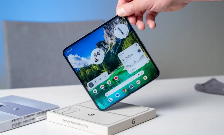 Hand holds open Google Pixel 10 Pro Fold showing weather and stock widgets.