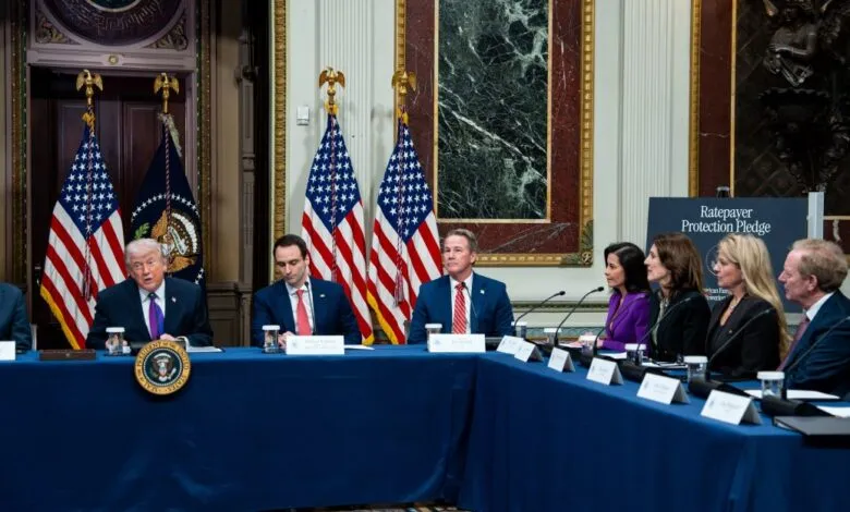 Donald Trump at a table with others, American flags behind him.