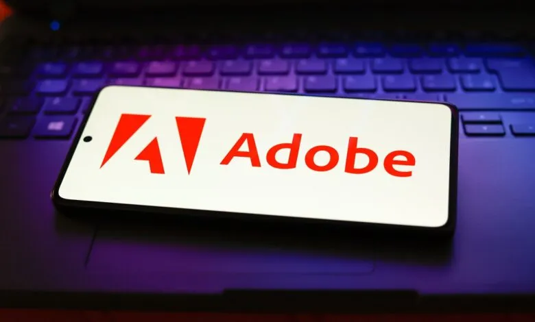 Adobe logo displayed on a smartphone screen resting on a laptop keyboard.