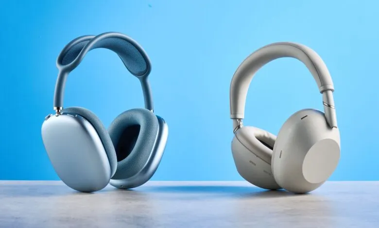 Two pairs of wireless headphones, one blue and one white, on a gray surface.