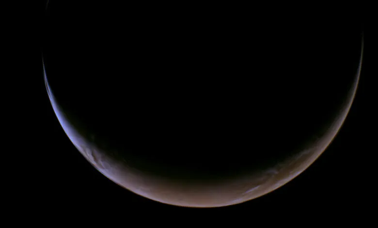 Crescent Mars glows against the blackness of space, showing atmospheric details.
