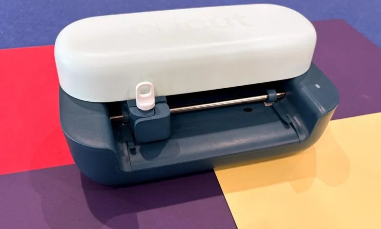 Cricut Joy 2 cutting machine on colorful paper background.