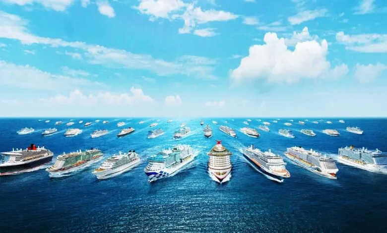 Large fleet of cruise ships sailing on a calm, blue ocean under a partly cloudy sky.