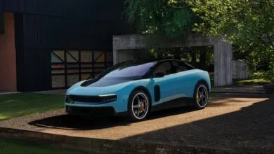 Light blue Ferrari sports car parked on concrete pad in front of modern house.