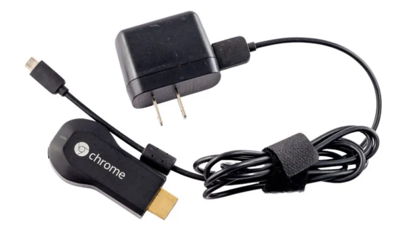 Google Chromecast dongle, power adapter, and cable on white background.