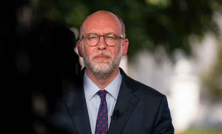 Russell Vought in suit and tie, wearing glasses, looking at camera.