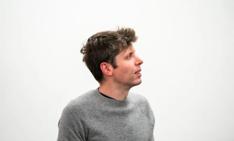 Man in gray sweater looking up against a white background.