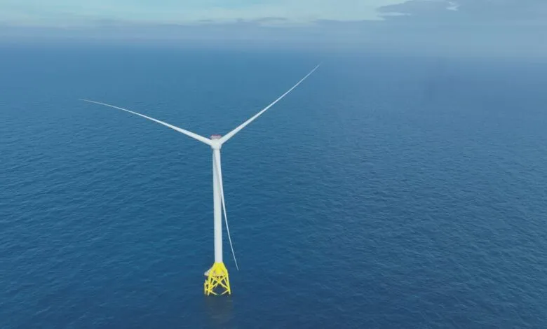 Offshore wind turbine stands in the ocean with blue water.
