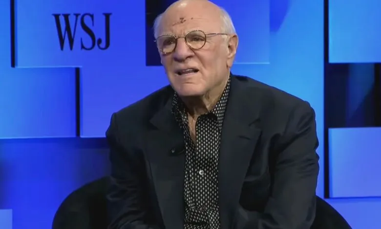 Barry Diller speaking at WSJ event, wearing glasses and a dark suit.